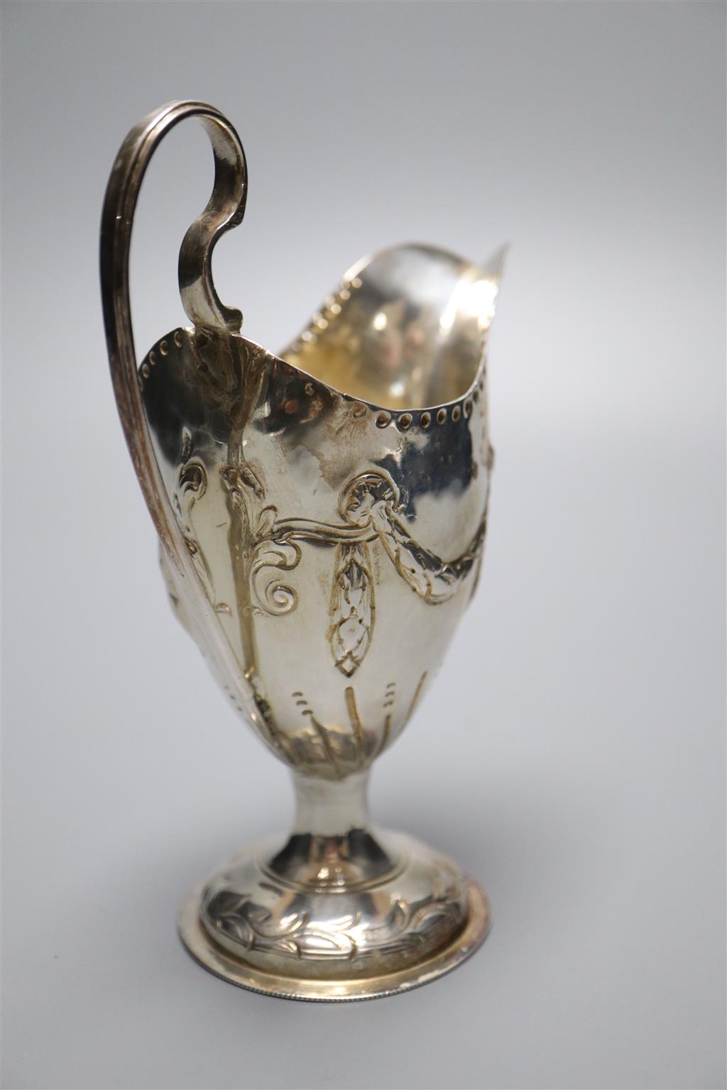 A George III silver helmet shaped cream jug, with later embossed decoration, London, 1773, 14cm, 88 grams (a.f.).